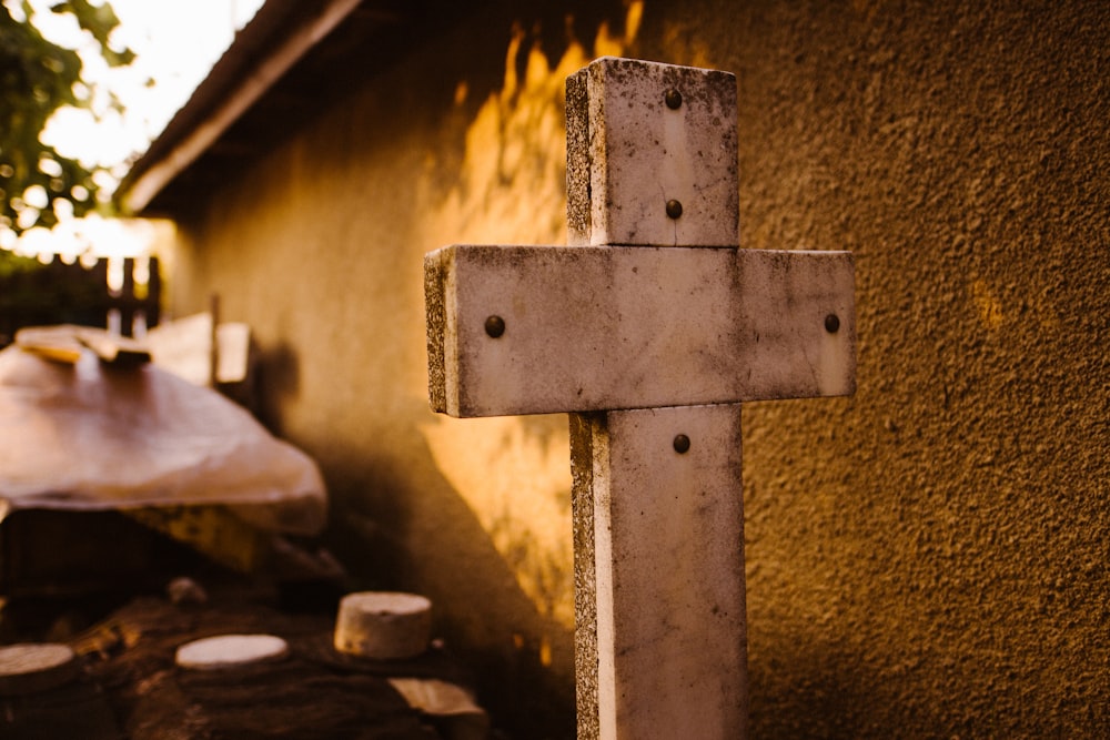 gray wooden cross on brown concrete wall