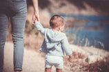 toddler's walking on the seashore with adult