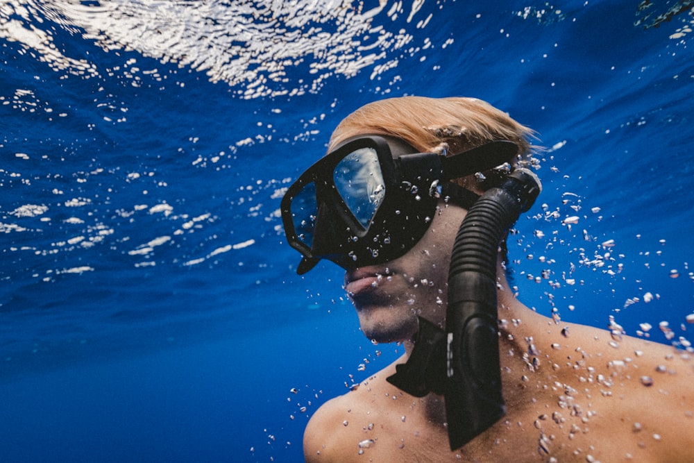 Mann mit schwarzer Schutzbrille unter Wasser