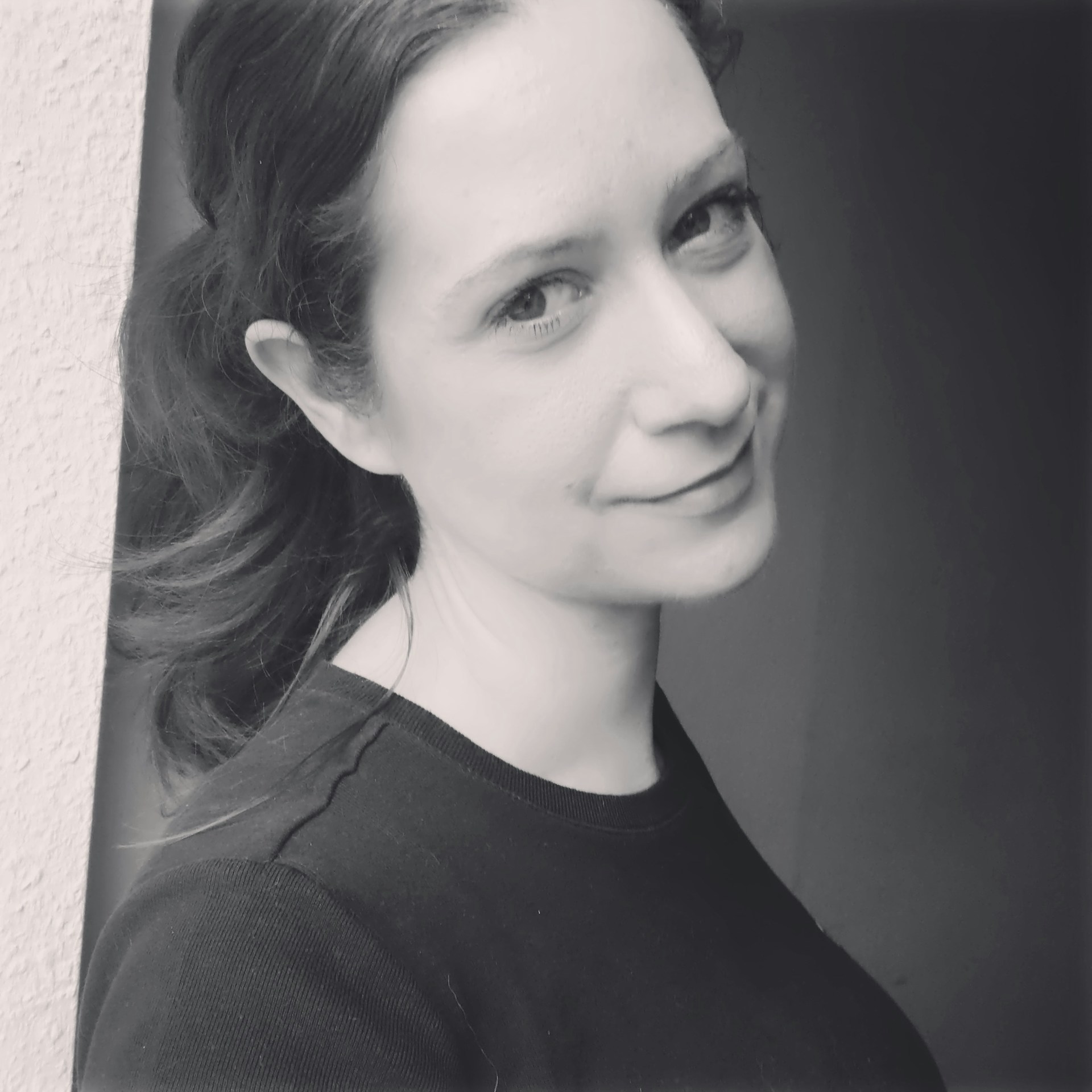 Artful black and white shot of a guest smiling softly, showcasing a fresh, fitness-friendly hairstyle that blends simplicity with elegance.