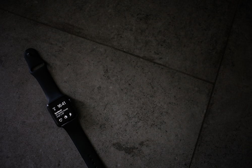 갈색 타일 위에 검은색 스포츠 밴드가 있는 스페이스 그레이 Apple Watch