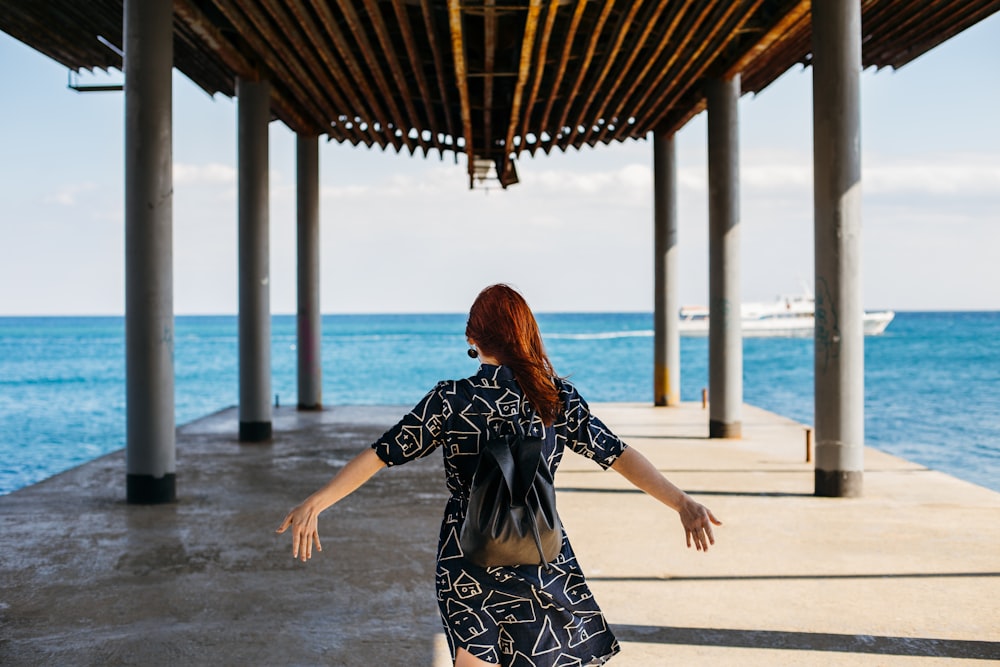 woman wearing black dress standing on dock during daytime