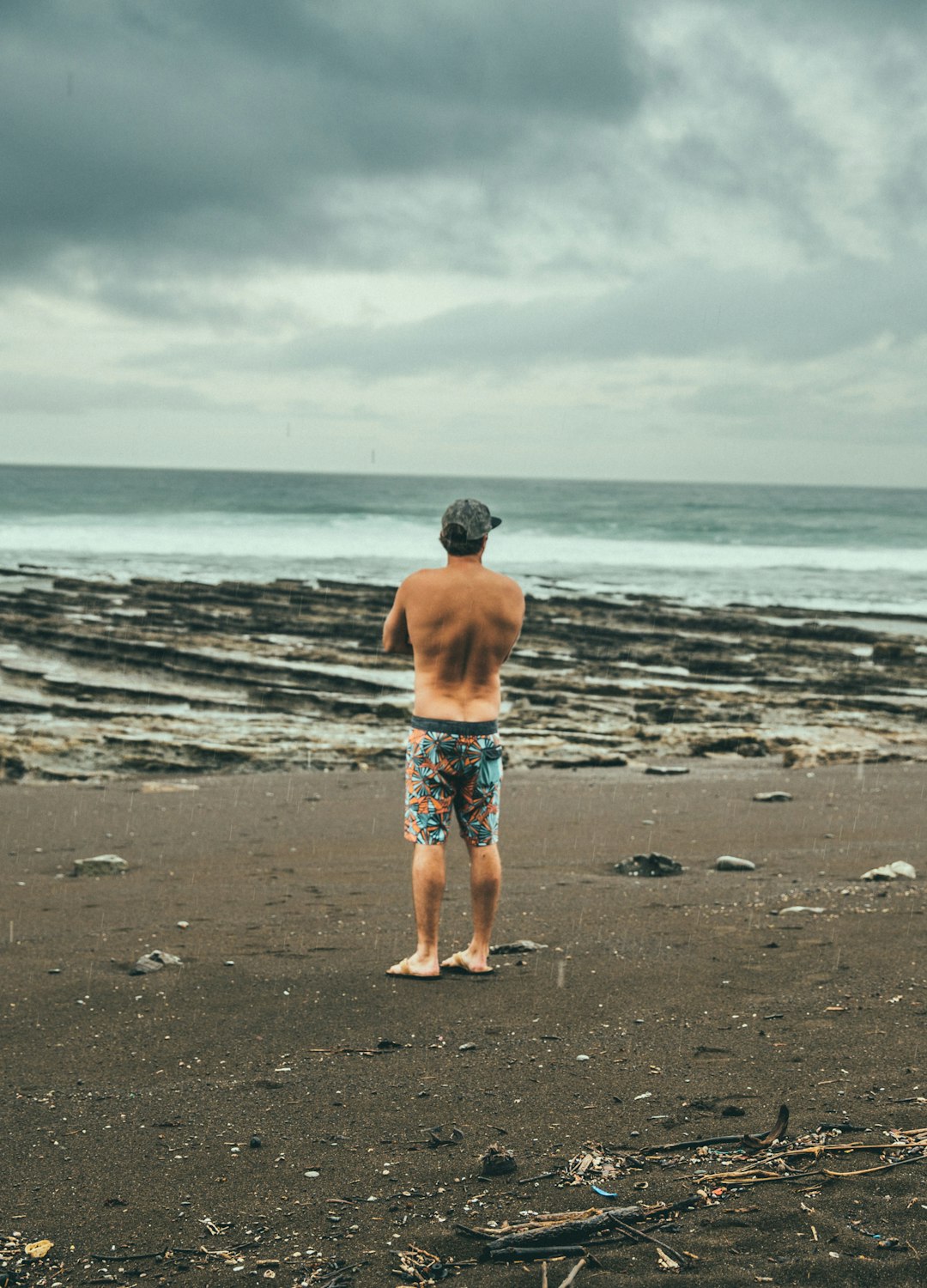 man in blue and white shorts standing on beach during daytime