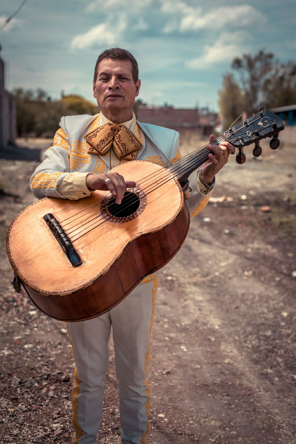 Hombre de pie sosteniendo una guitarra musical Brown Sting durante el día