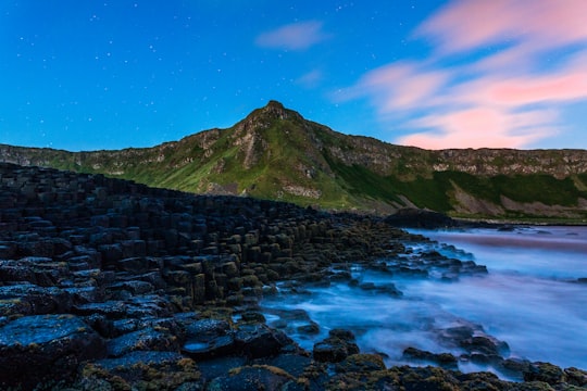 green grass mountain under blue sky and white clouds in Giant's Causeway United Kingdom