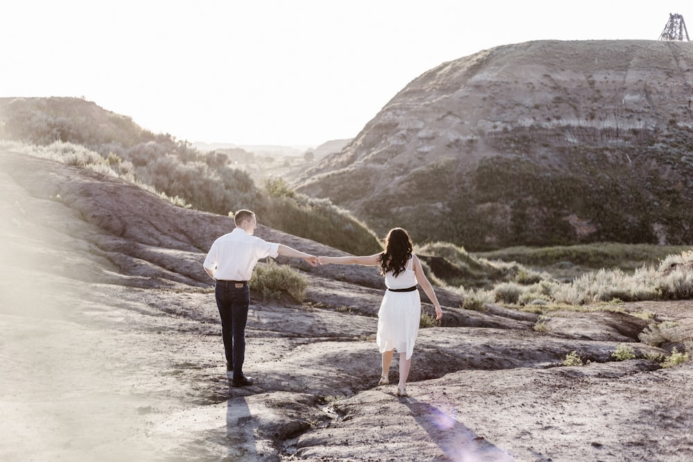 couple holding hands while walking along the rocky coastline