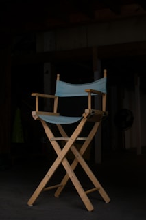 A close-up of a director's chair with a film set in the background.