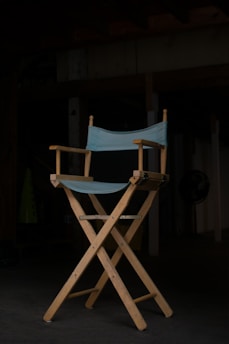 A casting room with a single spotlight illuminating a script resting on a vintage wooden chair.