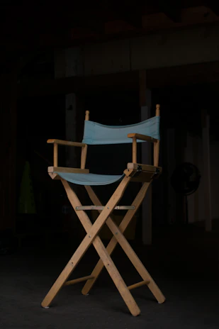 Close-up of a director’s chair with 'Malwa Studios' embroidered in gold, set against a dark, moody backdrop.