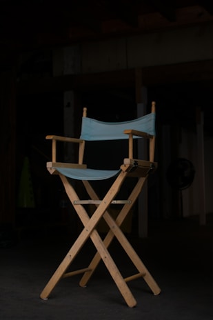 A director’s chair and clapperboard set against a blue-lit studio backdrop.