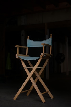 A close-up of a director’s chair with 'Harris Pictures' embroidered on the backrest on a busy set.