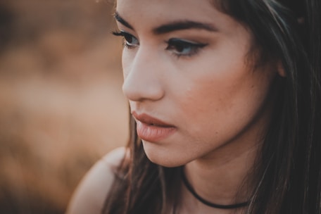 A warm, candid portrait of a young woman in natural light against a soft, neutral background.