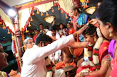 A vibrant wedding setup with colorful drapes and traditional Kerala lamps illuminating the space.