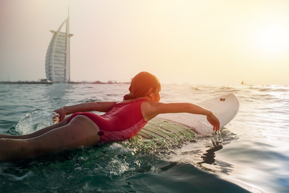 ragazza in cima alla tavola da surf bianca accanto a Burj Al Arab