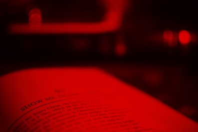 Close-up of an open book with glowing script in warm red tones.