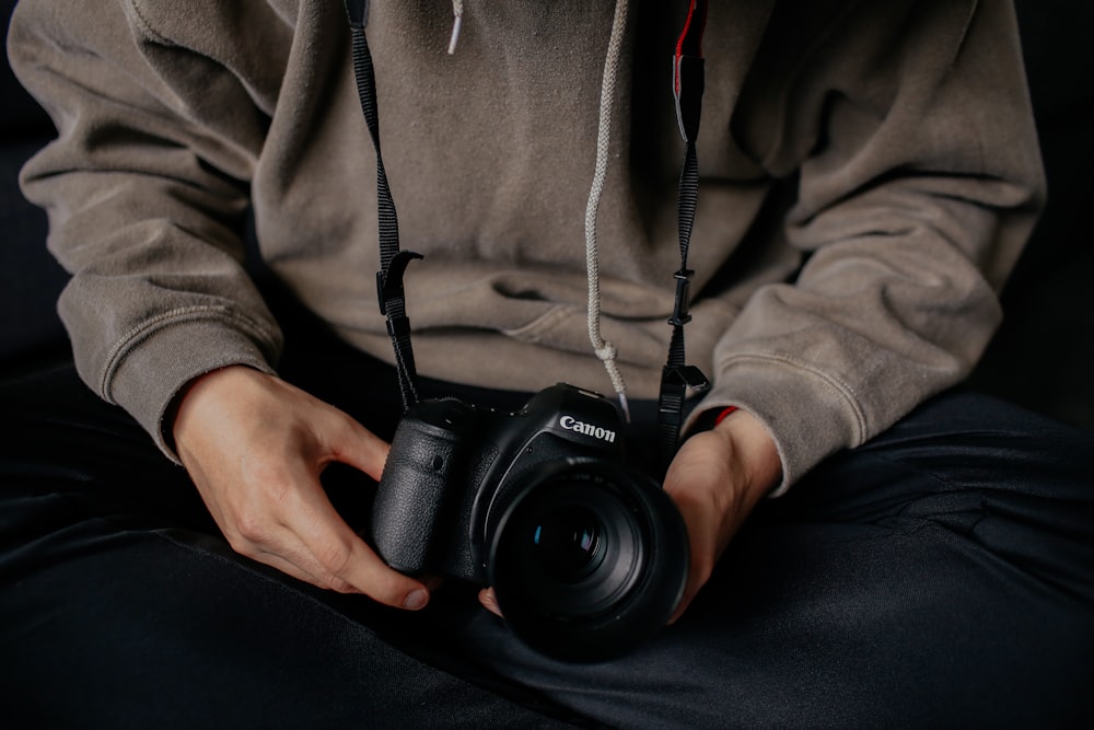 person holding black Canon DSLR