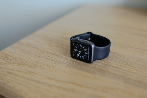 A sleek smartwatch with a glowing display resting on a wooden table.