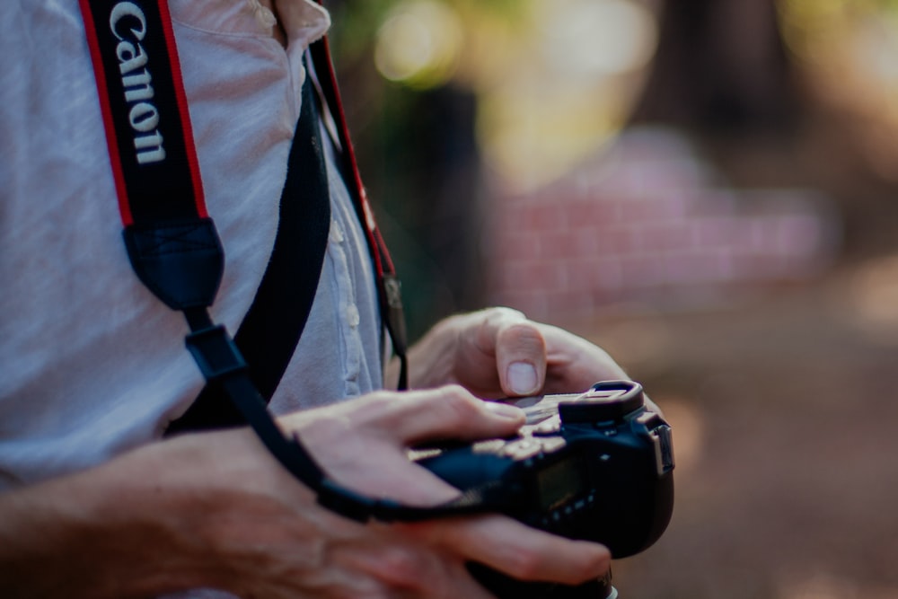 person holding black Canon DSLR camera