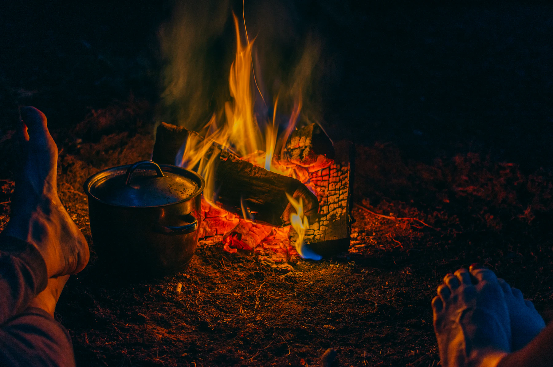 Pot beside a campfire during an outdoor cooking session