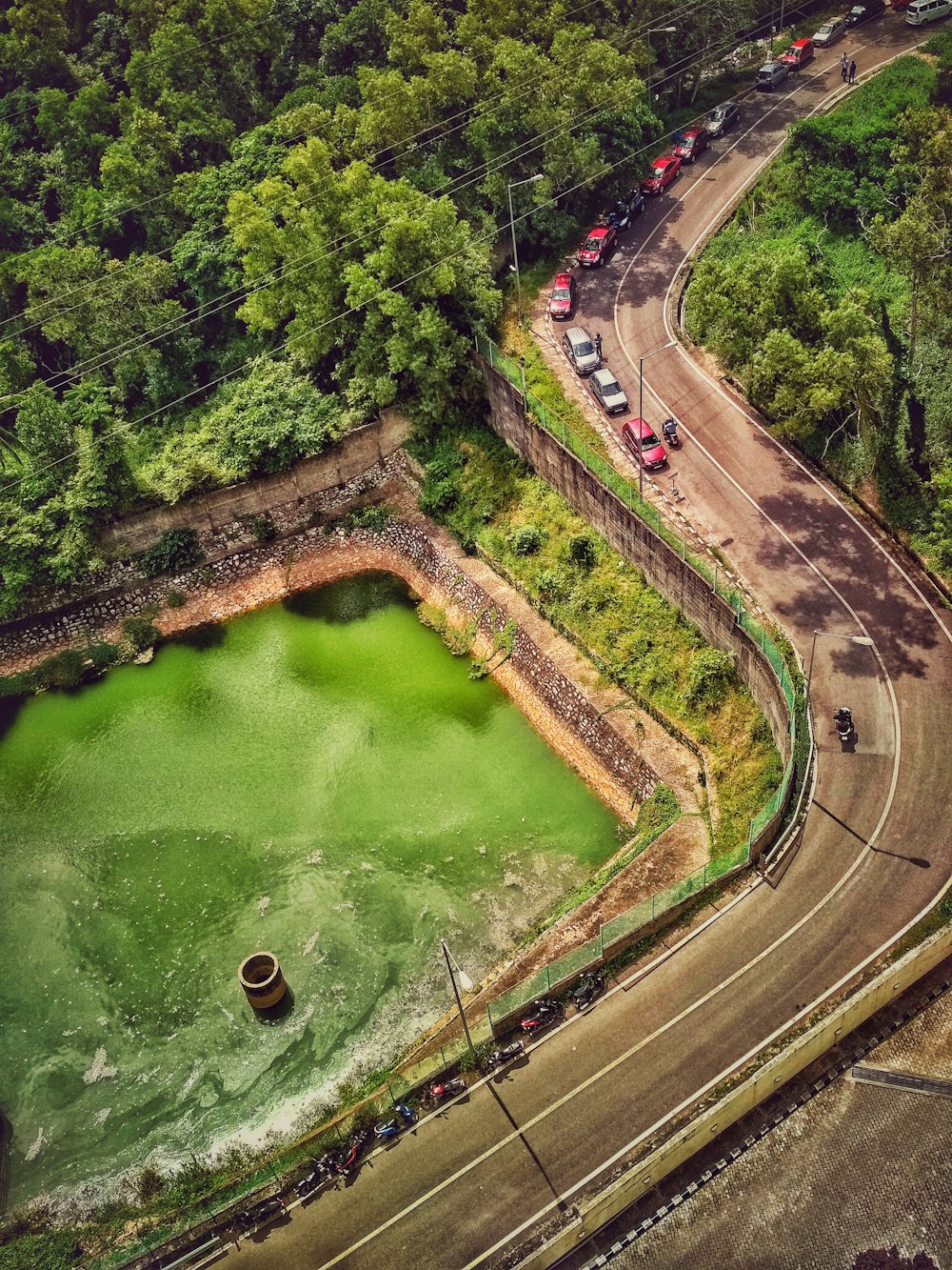 foto aerea di auto sulla strada vicino allo specchio d'acqua verde