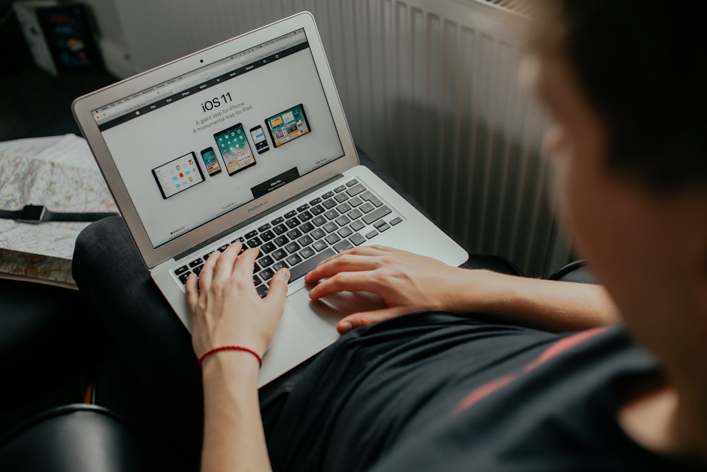 A person holding a MacBook with Apple website open on their lap