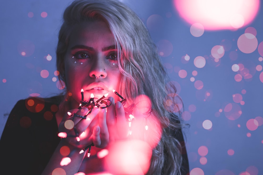 woman holding string lights