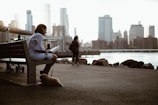 woman sitting on bench reading book with dog during daytime