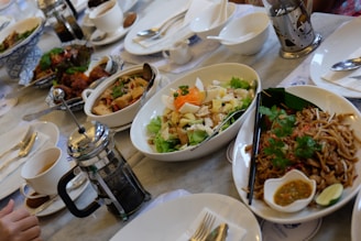 A vibrant dining table filled with various Thai dishes and cups of green tea and fresh coffee.
