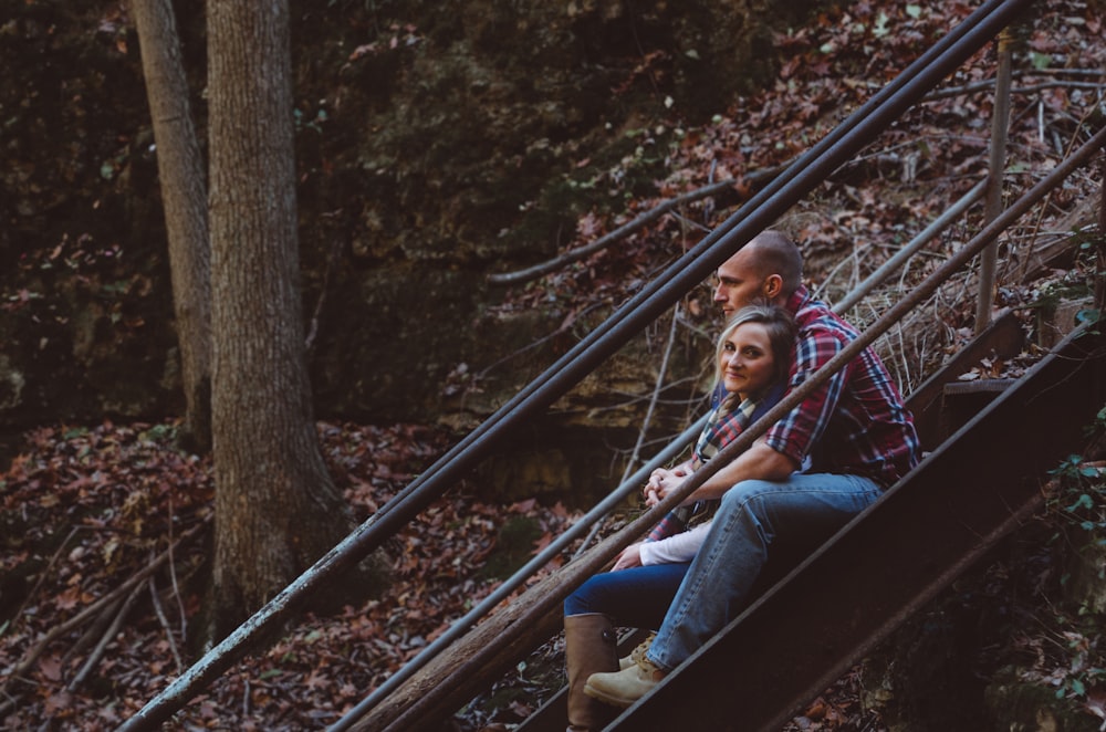 man in blue denim pants hugging woman on staircase during day time