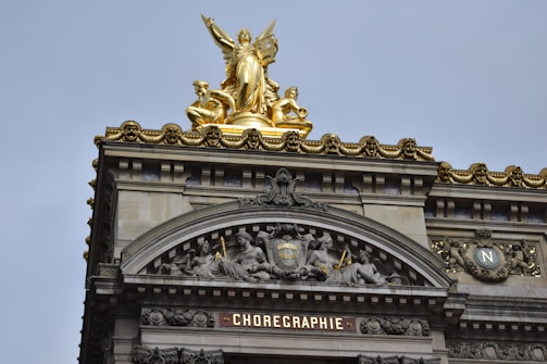 The image features an ornate architectural facade with elaborate carvings and a prominent gold statue at the top. The upper section includes detailed sculptures of figures and intricate designs, while the word 'CHOREGRAPHIE' is prominently displayed below.