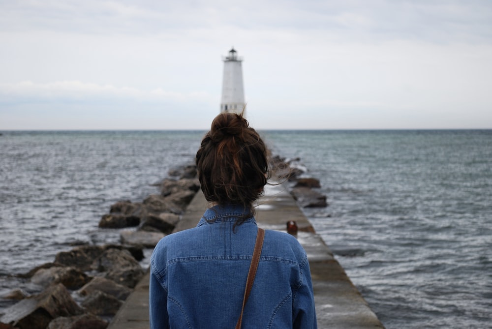 woman standing infront of lighthouse near beach