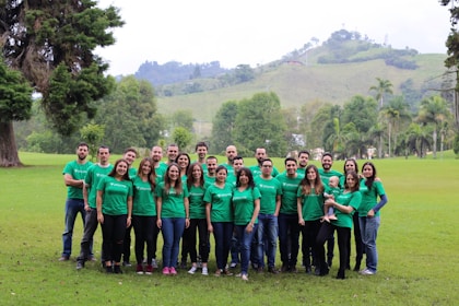 Happy employees wearing personalized green company apparel outdoors.