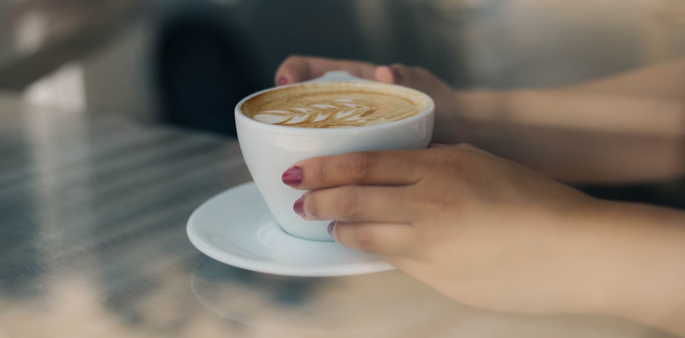 person holding white ceramic teacup