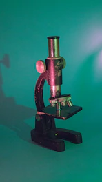 An antique ophthalmic microscope displayed on a wooden table with soft natural light.