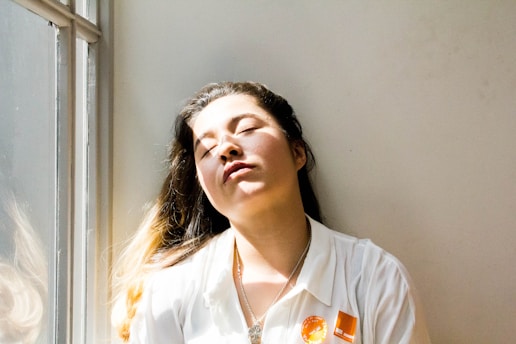 woman feeling tired and standing next to a window