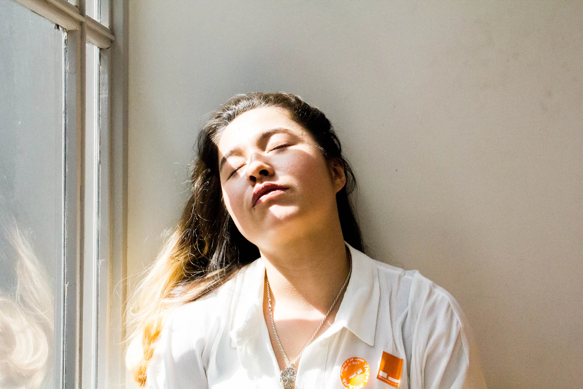 Woman standing at a window in morning daylight, which helps anchor the body clock