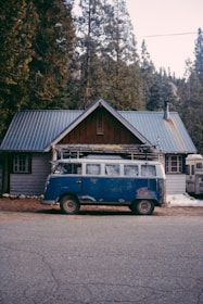 A delivery van parked in front of a rustic cabin.
