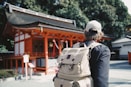man wearing black top and backpack near orange structure