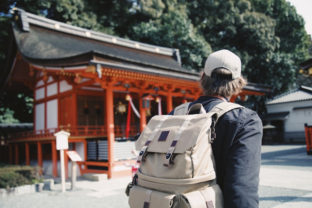 man wearing black top and backpack near orange structure