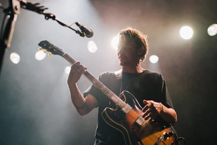 man playing guitar under spotlight