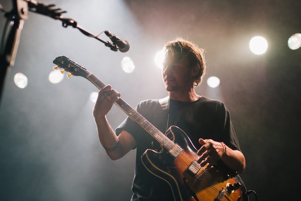 man playing guitar under spotlight