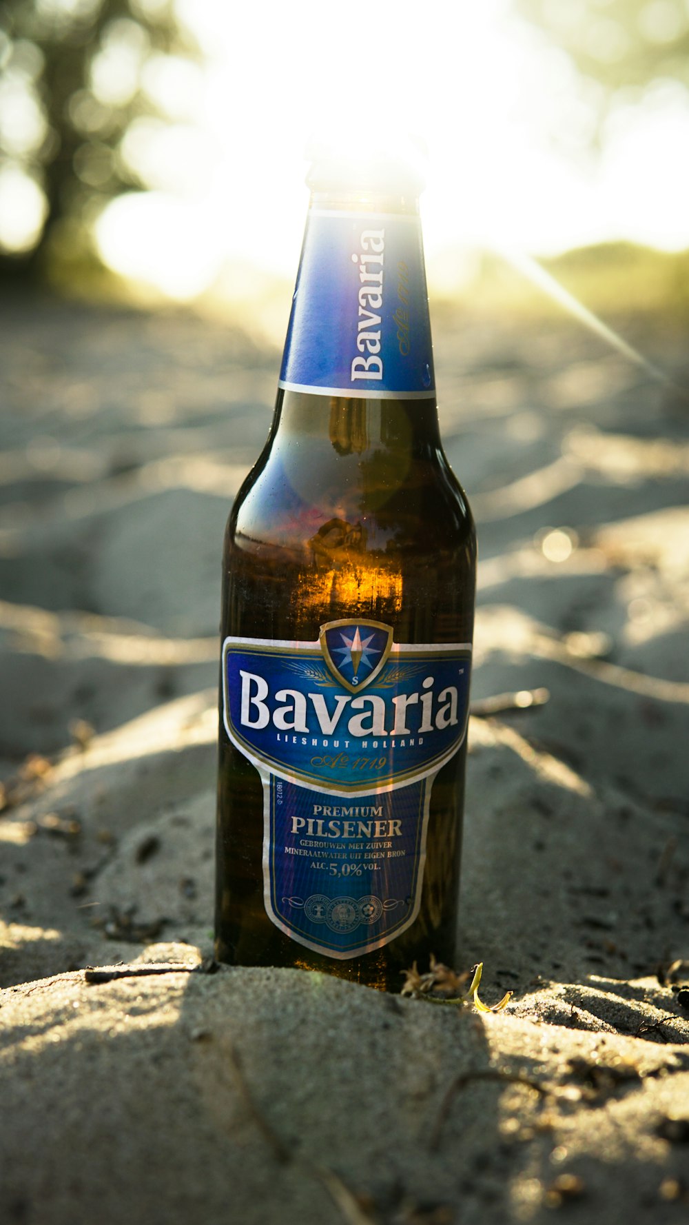 Botella de cerveza Bavaria Pilsener sobre arena