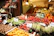 Bright, warm photo of a food market stall with fresh produce and happy customers.