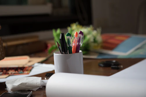 A cozy workspace with colorful personalized mugs and pens scattered around.