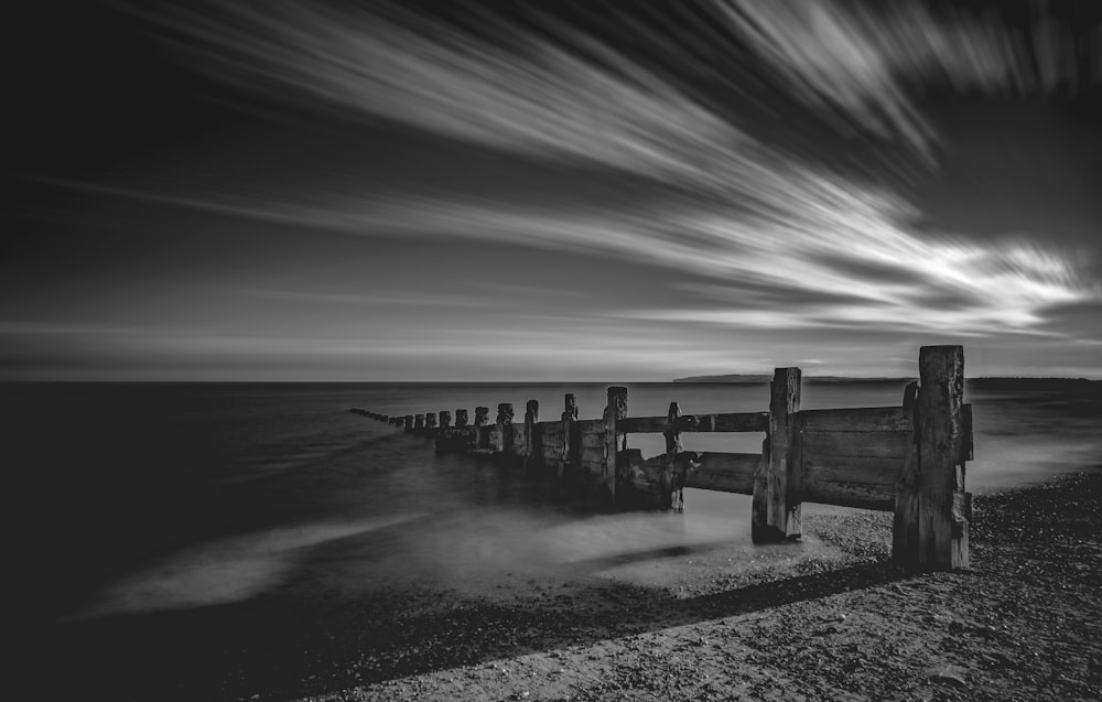 grayscale photo of wooden fence on sand