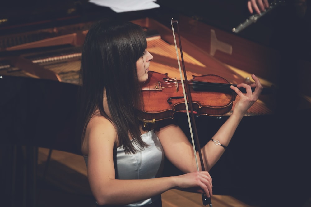 Mujer tocando el violín al lado del piano de cola