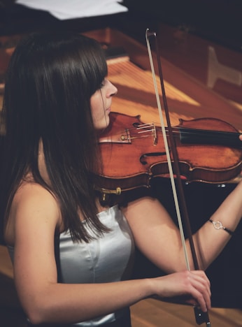 woman playing violin beside grand piano