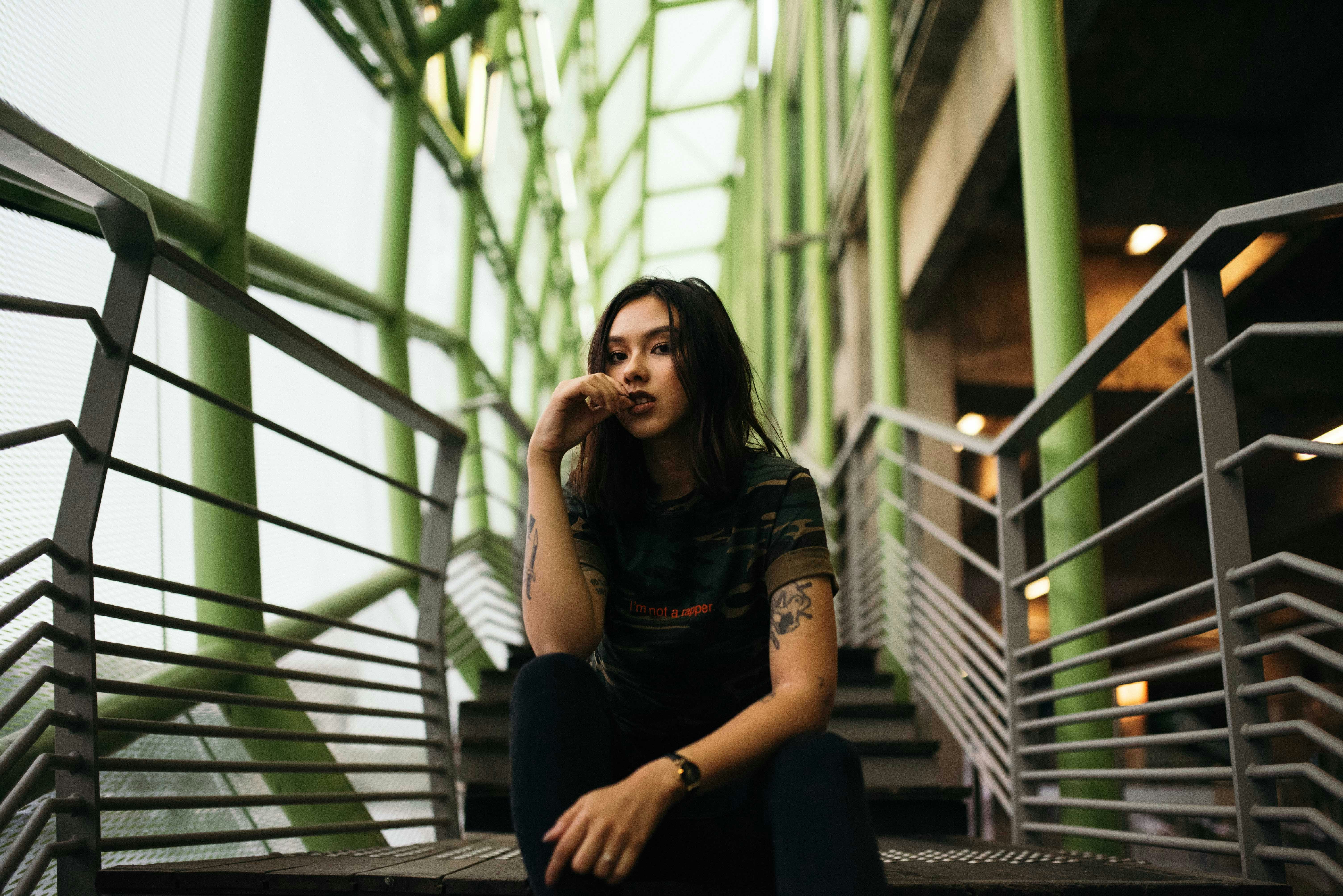 woman in black crew-neck top sitting on stair