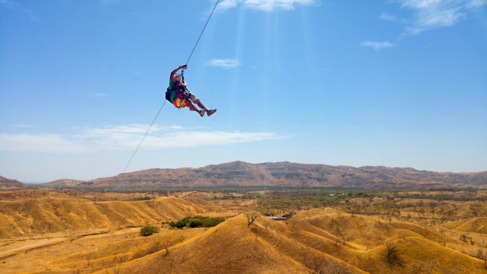Excited visitors enjoying a high-speed zipline against the scenic backdrop of Qiddiya hills.