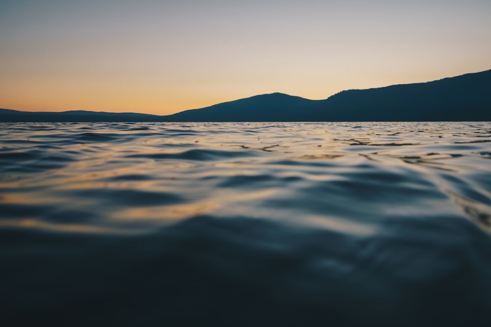 silhouette photo of mountain and water during dawn